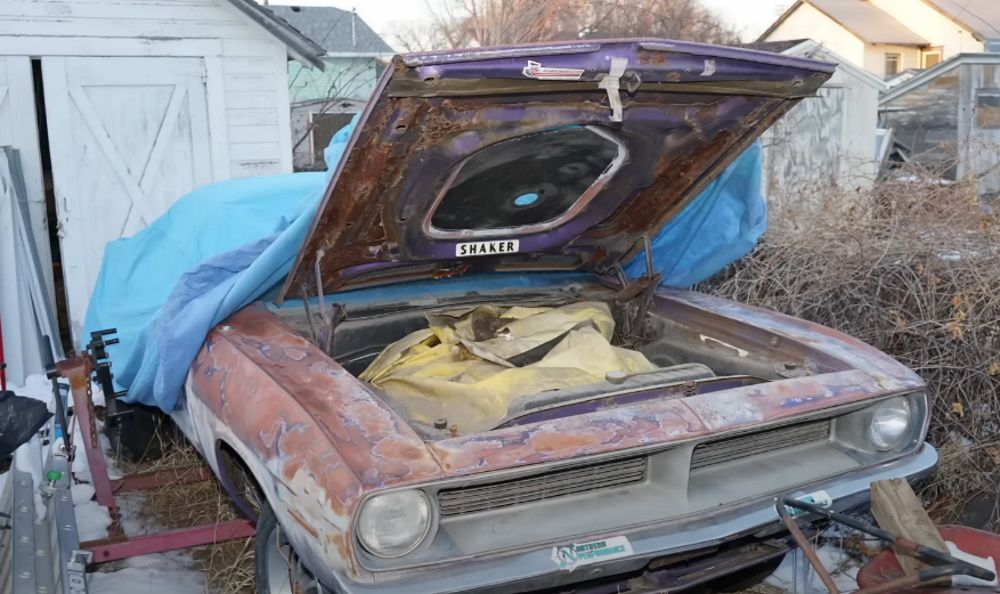 A 1970 Plymouth Cuda partially covered by a tarp