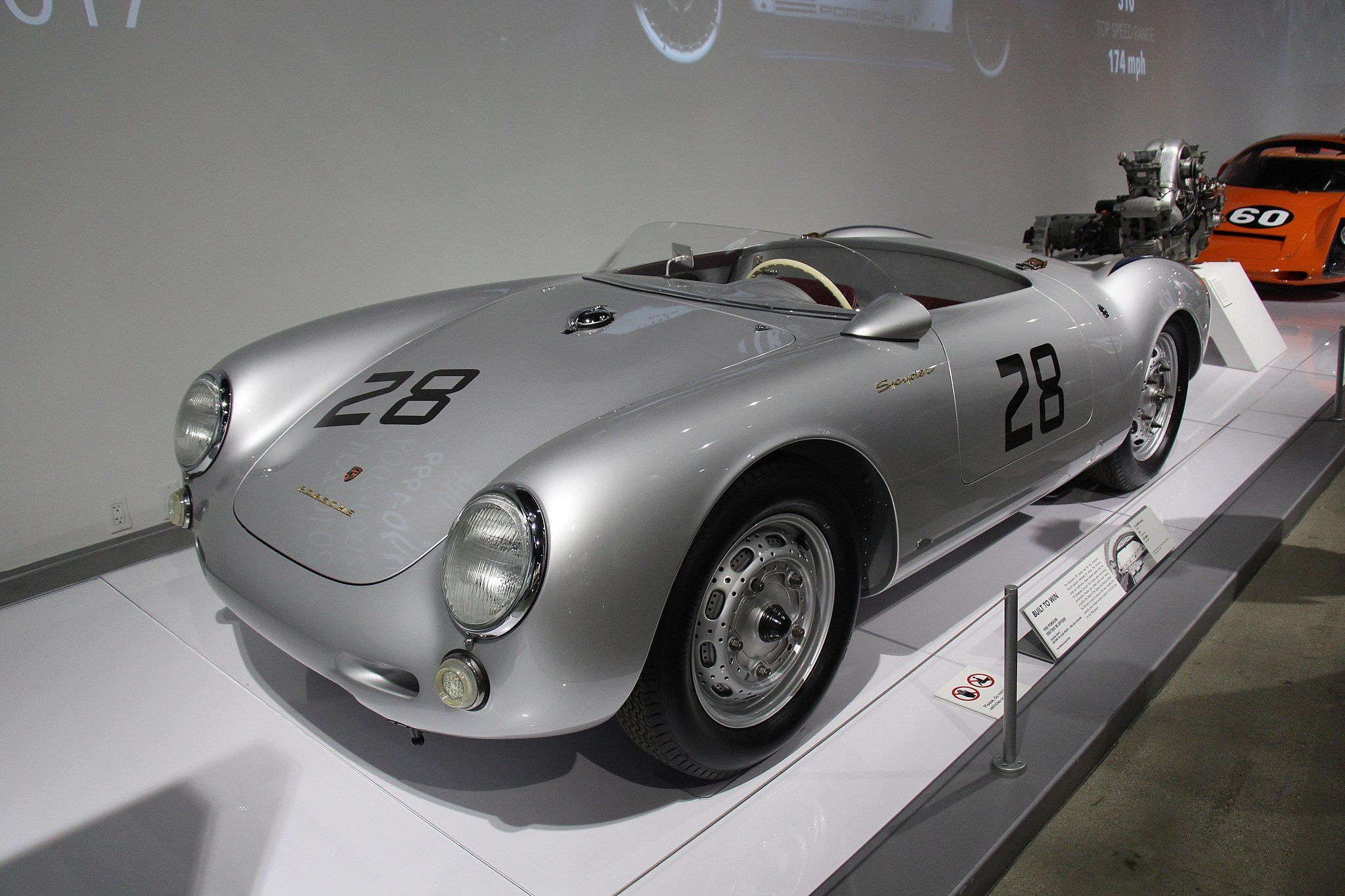 A silver Porsche 550 Spyder parked in a studio. 