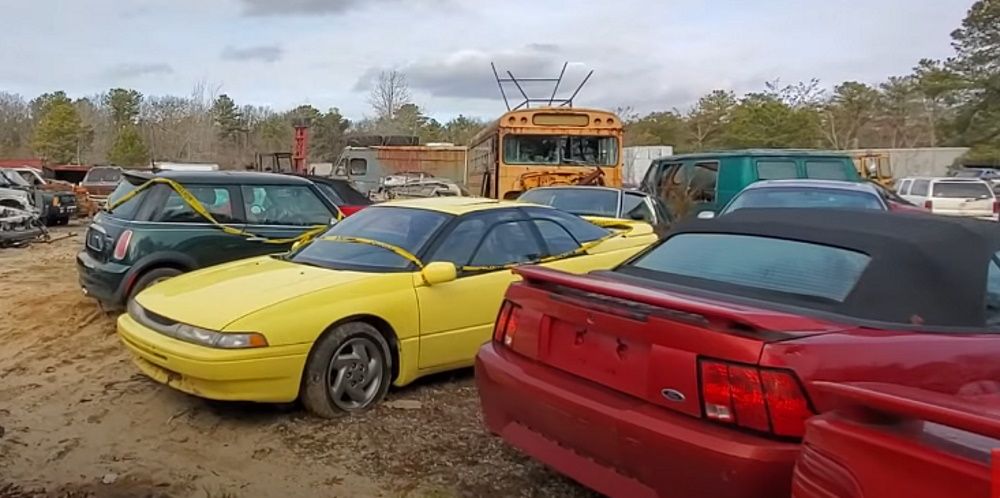 A yellow Subaru SVX among the car at a Long Island, NY, junkyard